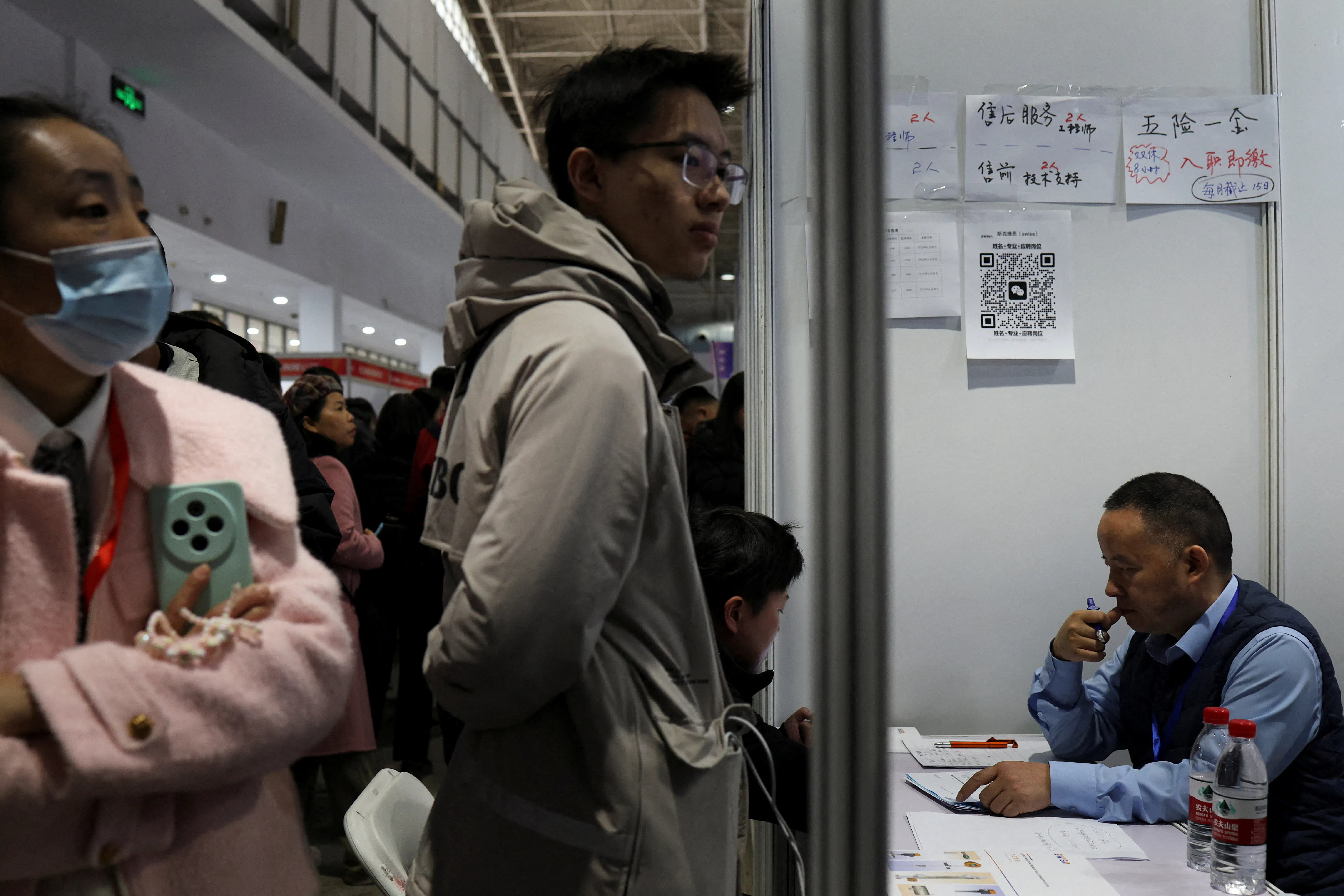 A recruiter attends to an applicant at a job fair in Beijing, China, 14 March 2026.