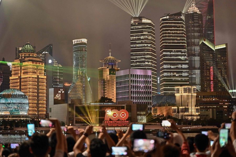 Spectators look at a light show on the Bund promenade in Shanghai, China, on 1 July 2021, as the country marks the 100th anniversary of the founding of the Communist Party of China. (Hector Retamal/AFP)