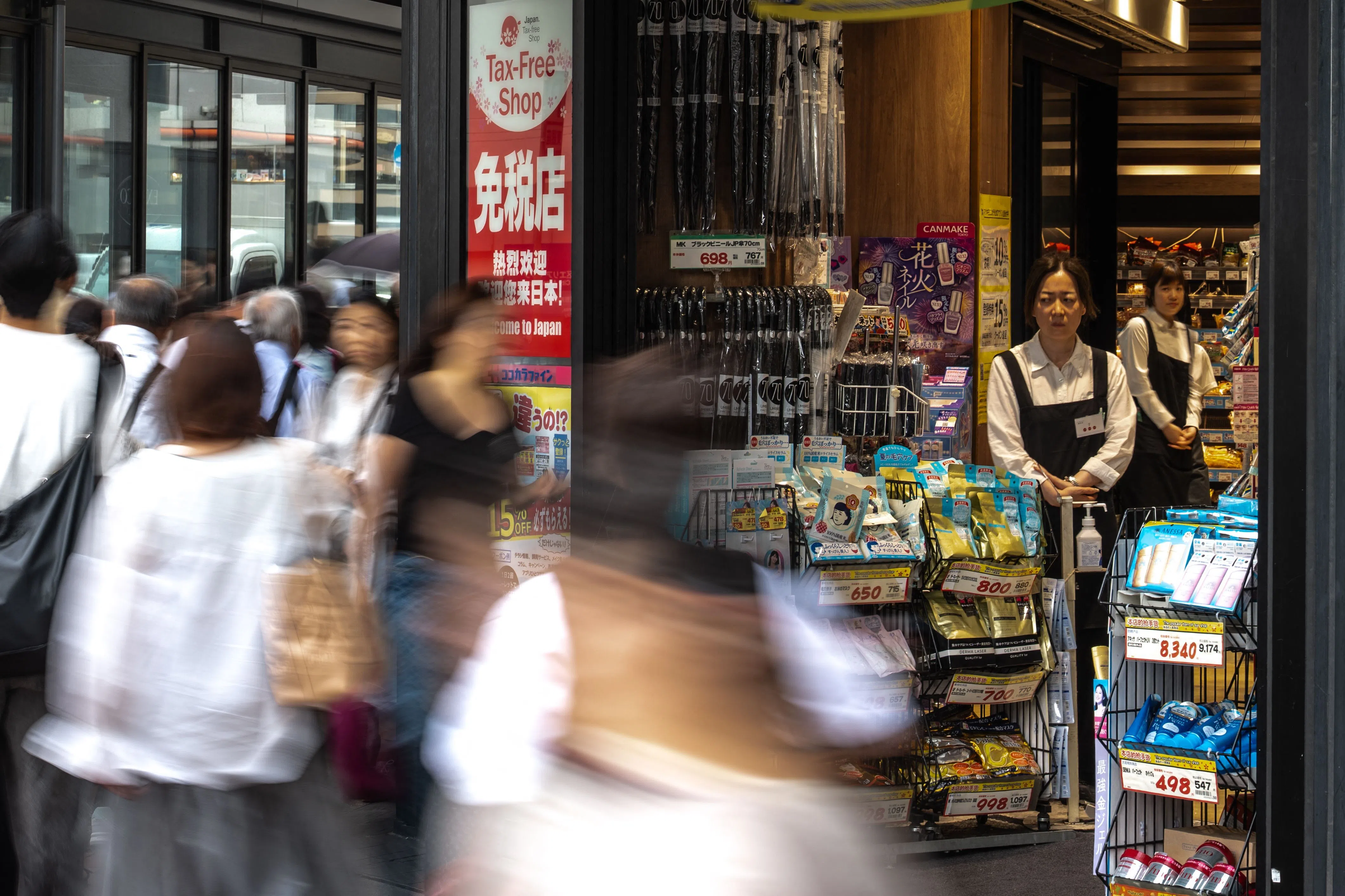 Staff members of a tax-free shop watch as pedestrians walk past at the Ginza shopping district in Tokyo on 21 August 2026.