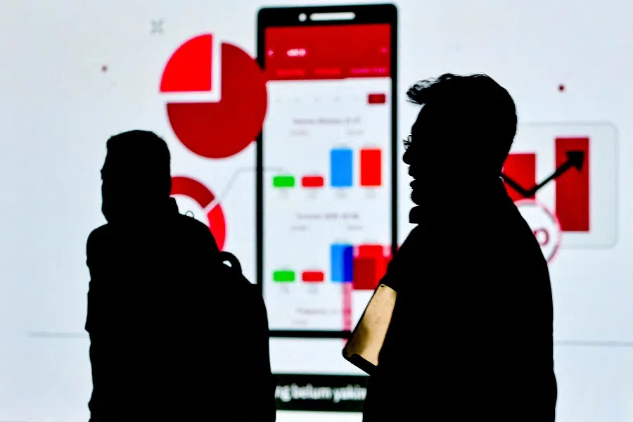 People walk past a large screen displaying advertisements for investing in shares of the Indonesia Stock Exchange in Jakarta, Indonesia, on 14 March 2024. (Bay Ismoyo/AFP)