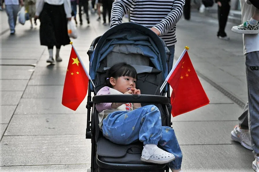 A child rests in a stroller adorned with Chinese flags as her mother pushes her in the Qianmen area of Beijing, China, on 3 May 2023. (Greg Baker/AFP)