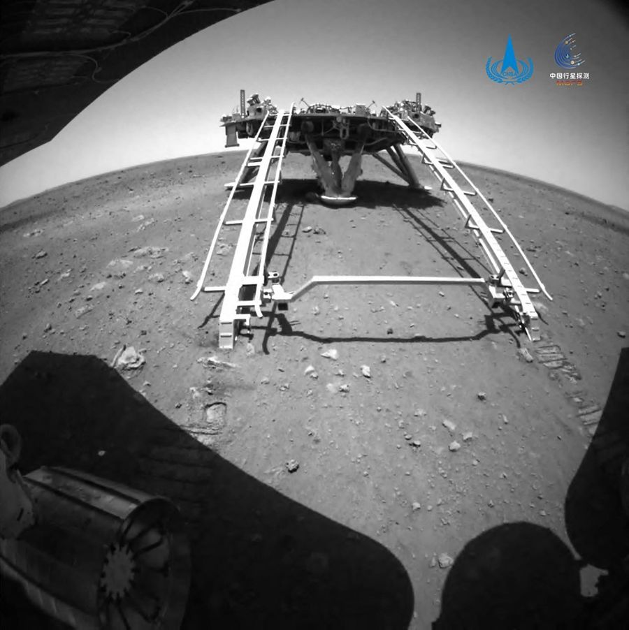 This handout photograph released on 22 May 2021 by the China National Space Administration (CNSA) shows an image taken by the rear obstacle avoidance camera of China's Zhurong Mars rover showing the landing platform of the Tianwen-1 Mars probe, after the rover drove down the ramp onto the surface of Mars. (Handout/China National Space Administration (CNSA)/AFP)