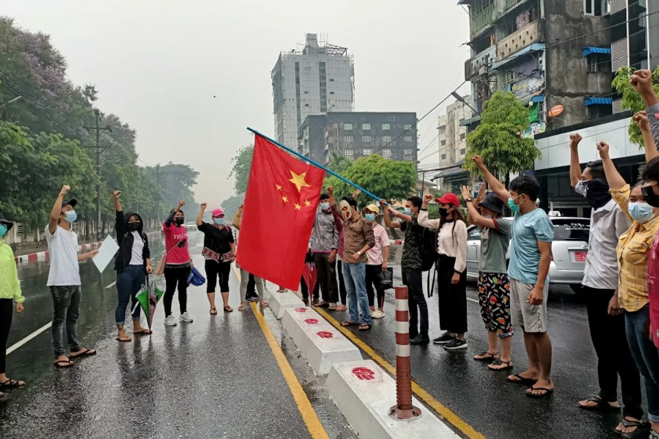 Anti-coup protesters hold a Chinese flag before burning it down during a demonstration against China in Yangon, Myanmar, 5 April 2021. (Stringer/Reuters)