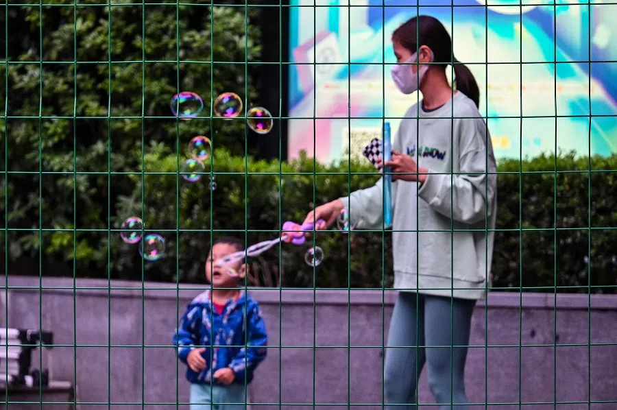 A woman and a child are seen through a fence closing an area in lockdown in Changning district, after new Covid-19 cases were reported in Shanghai, China, on 8 October 2022. (Hector Retamal/AFP)
