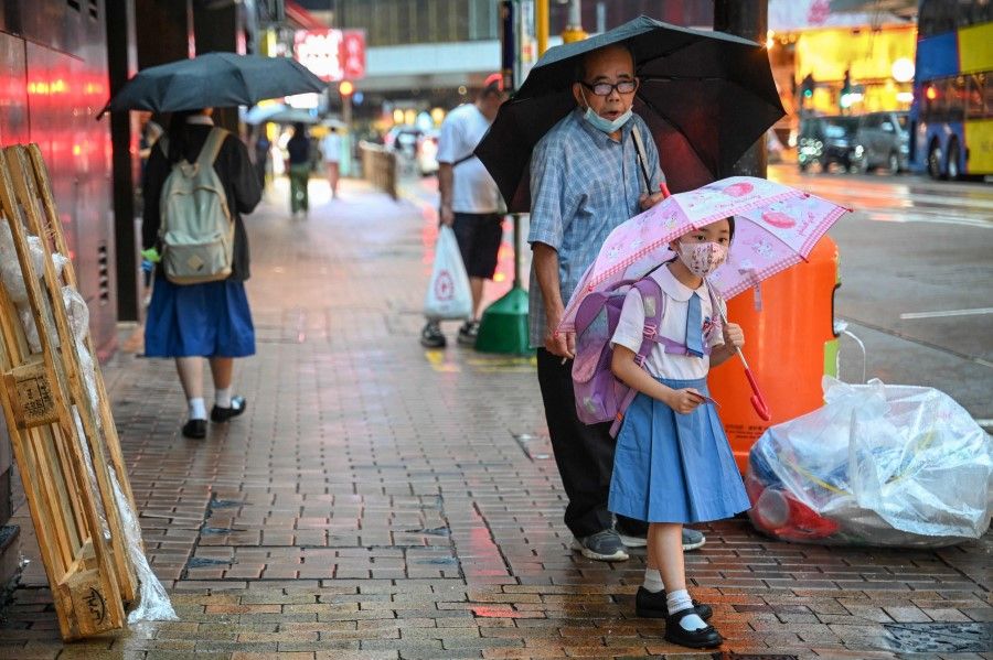 Pedestrians cross a street in the rain in Hong Kong on 18 October 2023. (Peter Parks/AFP)