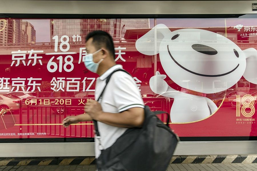 A pedestrian wearing a protective mask walks past an advertisement for China's mid-year shopping festival of JD.com in Beijing, China, 27 May 2021. (Qilai Shen/Bloomberg)