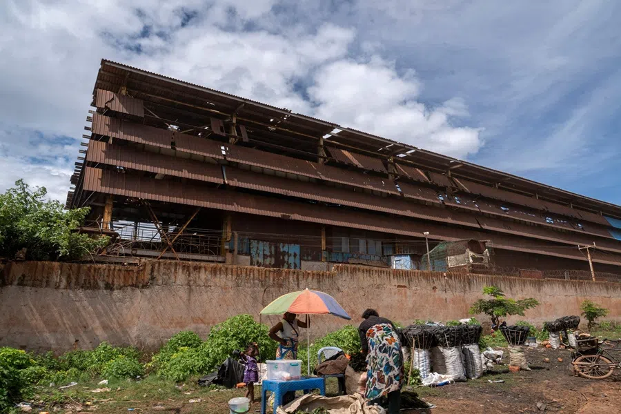 A woman sells food and charcoal at her stall outside the walls of the Chinese mining company Congo Dongfang Mining (CDM) in Lubumbashi on 24 November 2025.