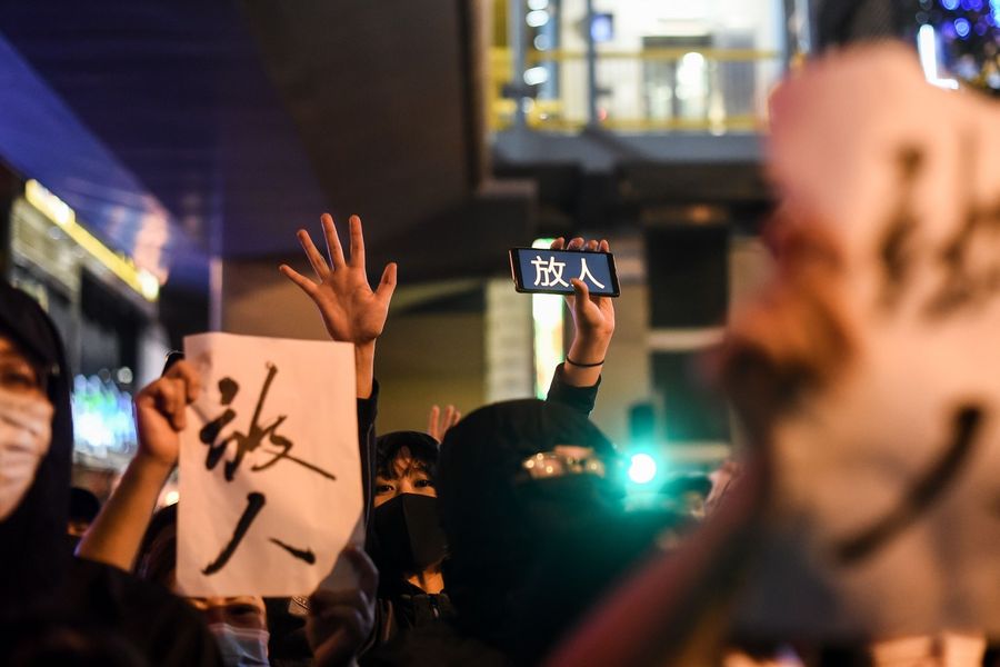 People chant slogans and hold the words "release (the protesters)" near a police-cordoned area to show support for a small group of protesters barricaded for over a week inside the Hong Kong Polytechnic University campus in Hung Hom district in Hong Kong on November 25, 2019. (Ye Aung Thu/AFP)