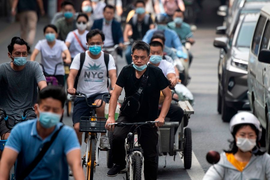 People commute on a street during the morning rush hour in Beijing on 20 July 2020. (Noel Celis/AFP)