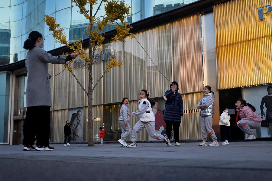 This picture taken on on 14 November 2022 shows a group of children playing rope skipping outside a mall after school in Beijing, China. (Wang Zhao/AFP)