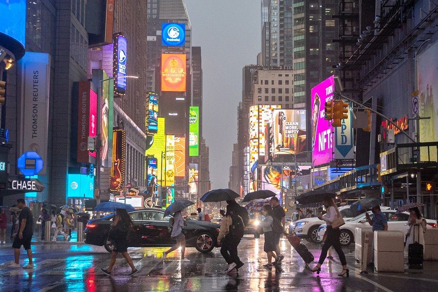 People walk in the rain in Times Square in New York City, New York, US, 6 July 2021. (Jeenah Moon/Reuters)