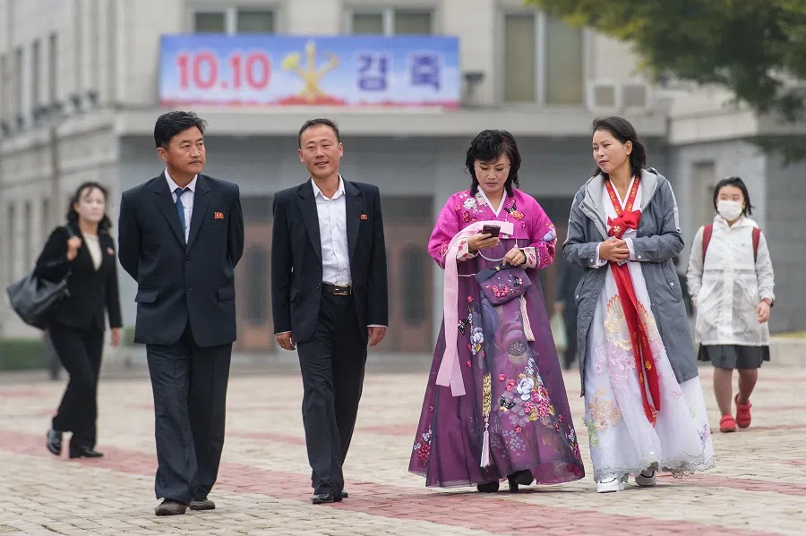 Pedestrians walk in front of a sign displayed on the occasion of the 78th founding anniversary of the Workers' Party of Korea in Pyongyang on 10 October 2023. (Kim Won Jin/AFP)