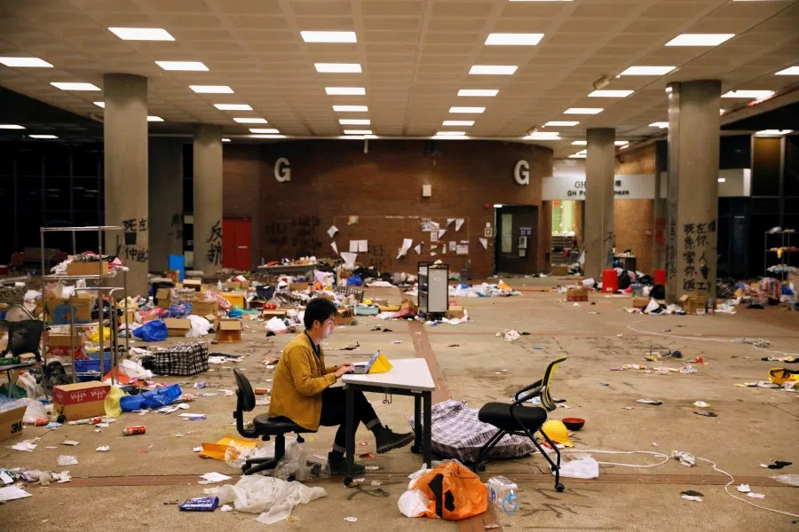 A journalist works on his laptop amid items left behind by protestors in Hong Kong Polytechnic University (PolyU) in Hong Kong, China, 26 November 2019. (Adnan Abidi/Reuters)