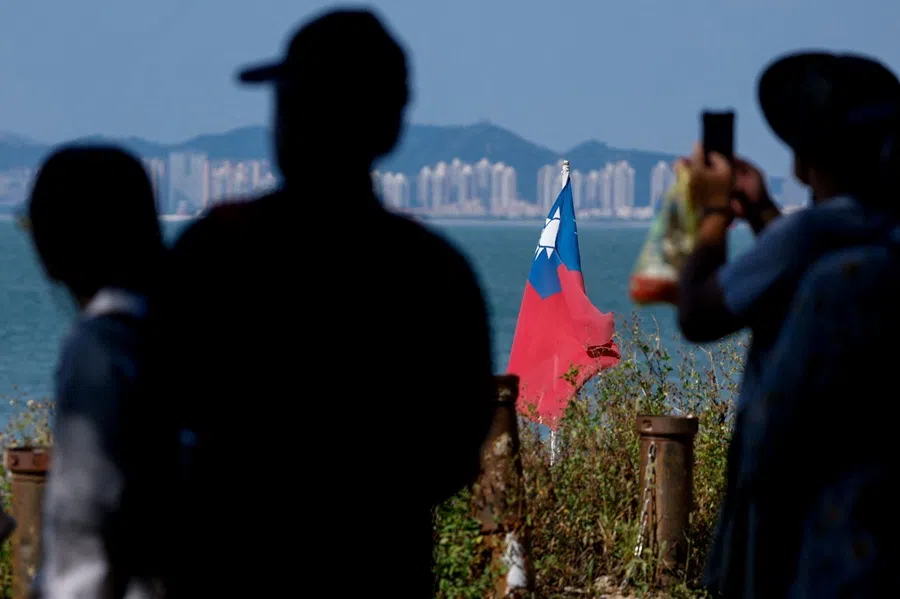 People take photos as a Taiwan flag flies, with China's Xiamen in the background, on Dadan Island, in Kinmen, Taiwan, 18 October 2025.