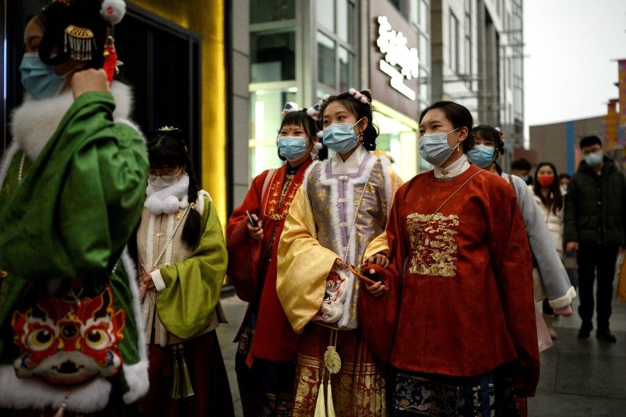 People in traditional attire walk along Wangfujing shopping street in Beijing on 14 February 2021. (Noel Celis/AFP)