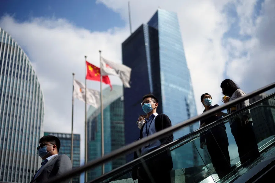 People wearing face masks following the Covid-19 outbreak ride an escalator past office towers in the Lujiazui financial district of Shanghai, China, 17 October 2022. (Aly Song/Reuters)