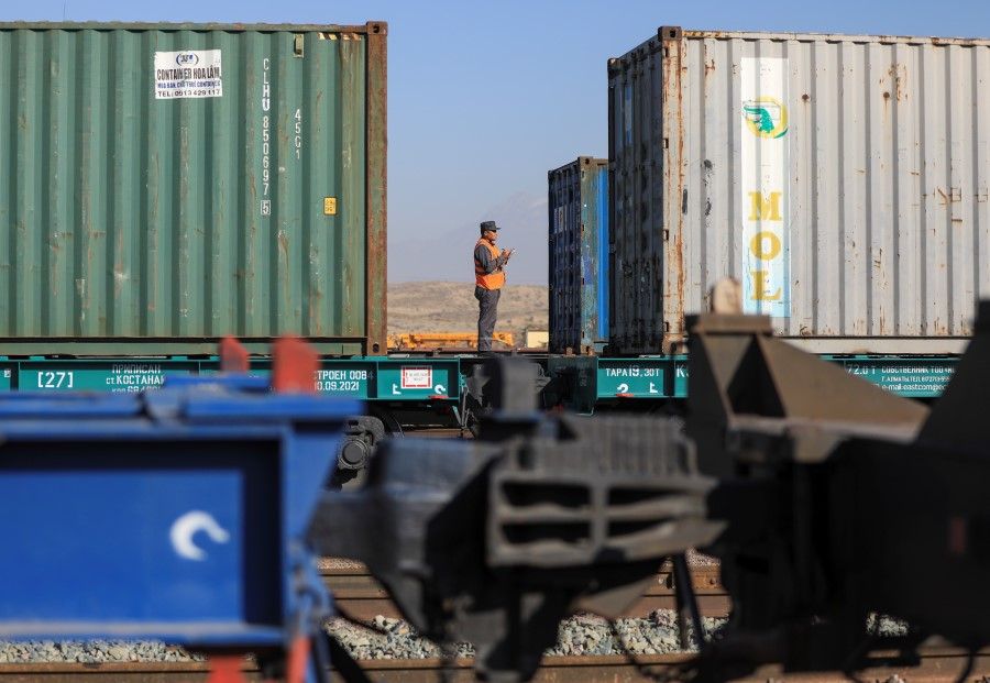 A railway worker checks shipping containers at the Altynkol railway station near the Khorgos border crossing point on the border with China in Kazakhstan, 26 October 2021. (Pavel Mikheyev/Reuters)
