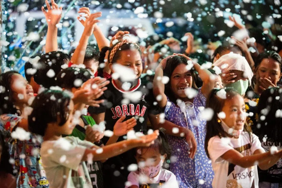 Children enjoy fake snow outside a Christmas-themed house, in Manila, Philippines, 11 December 2022. (Lisa Marie David/Reuters)