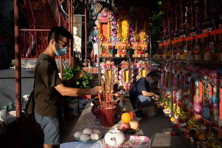 A man (left) offers incense sticks to his ancestors at a temple in Hong Kong on 21 August 2021, marking the Hungry Ghost Festival. (Bertha Wang/AFP)