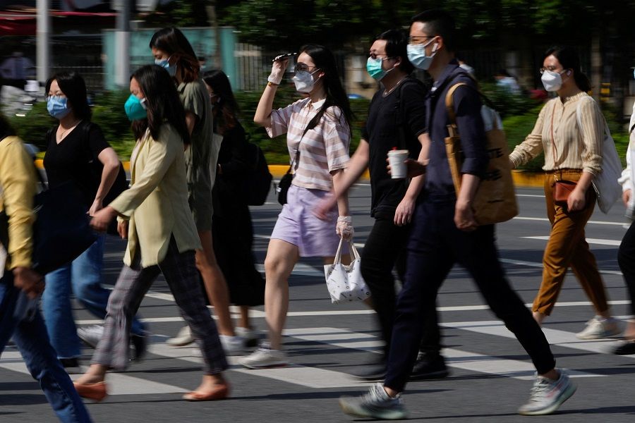 People wearing protective face masks walk on a street during morning rush hour in Shanghai, China, 6 June 2022. (Aly Song/Reuters)