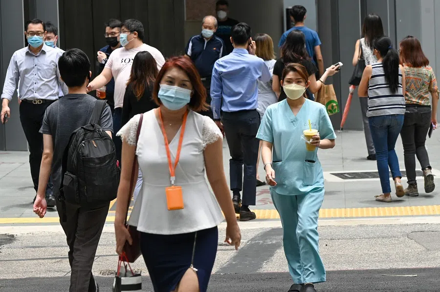 People walk out during lunch break at the Raffles Place financial business district in Singapore on 14 September 2021. (Roslan Rahman/AFP)