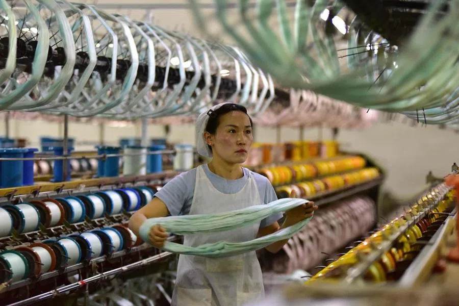A woman works on a silk production line at Anhui Jingjiu Silk Company in Fuyang city, in China's eastern Anhui province, 16 April 2026. (CN-STR/AFP)