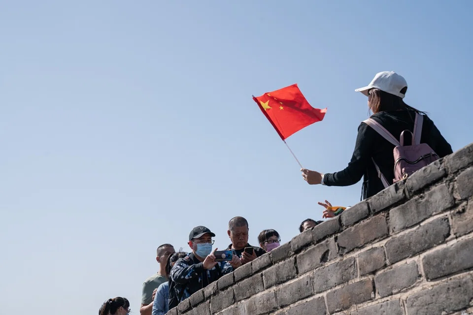A visitor holds a Chinese flag while posing for a photograph at the Badaling section of the Great Wall in Beijing, China, on 1 October 2020. (Yan Cong/Bloomberg)