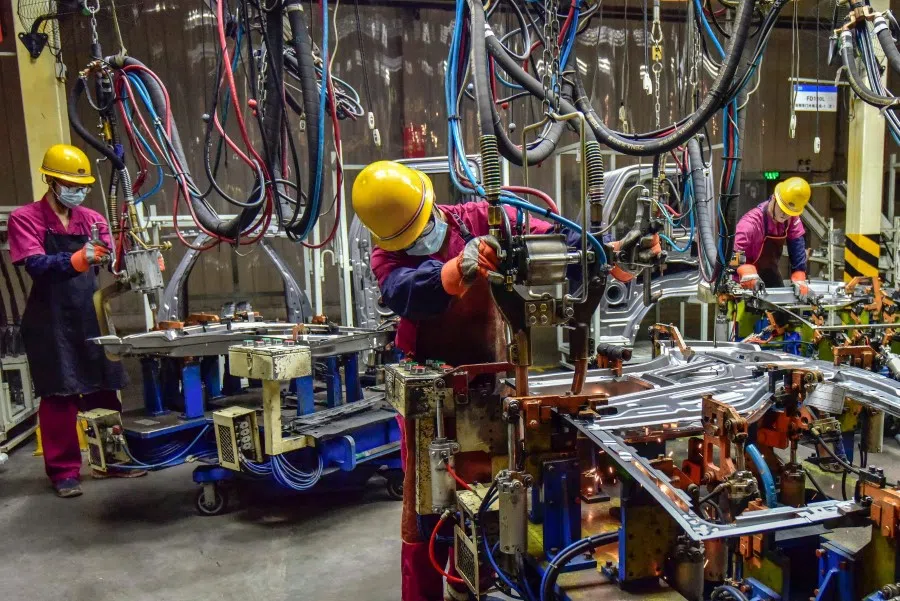 This file photo taken on 28 September 2021 shows workers assembling vehicles at a factory in Qingzhou, in China's eastern Shandong province. (STR/AFP)