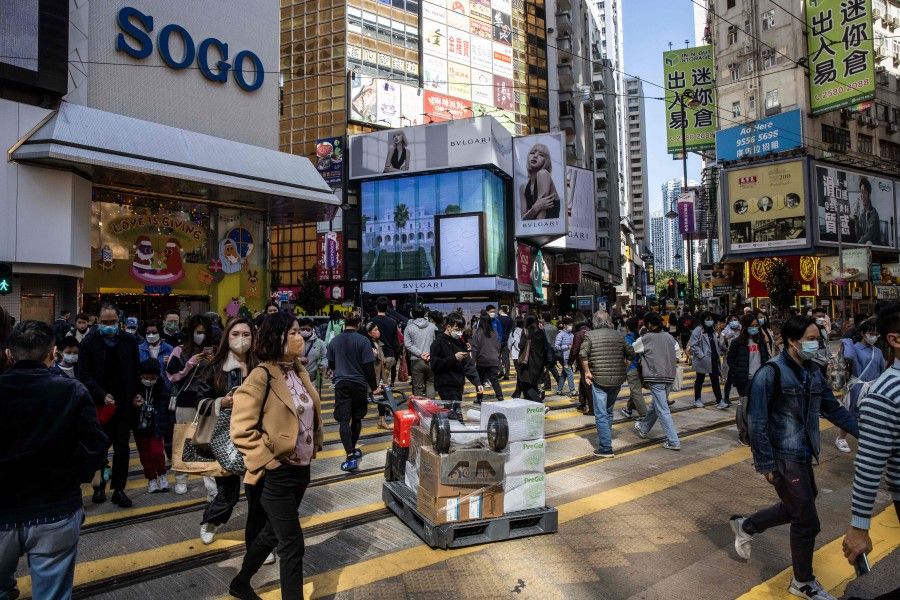 People walk through a shopping district in Hong Kong on 22 December 2022. (Isaac Lawrence/AFP)