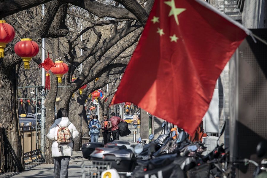 Pedestrians pass a Chinese flag in Beijing, China, on 3 March 2022. (Qilai Shen/Bloomberg)