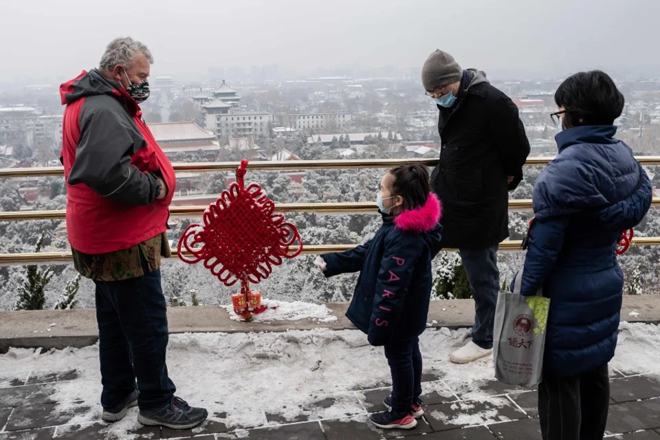 A girl (C) greets a foreigner living in Beijing at Jingshan Park. The Chinese government published draft regulations on permanent residence for foreigners in China, to seek public views. (Nicolas Asfouri/AFP)