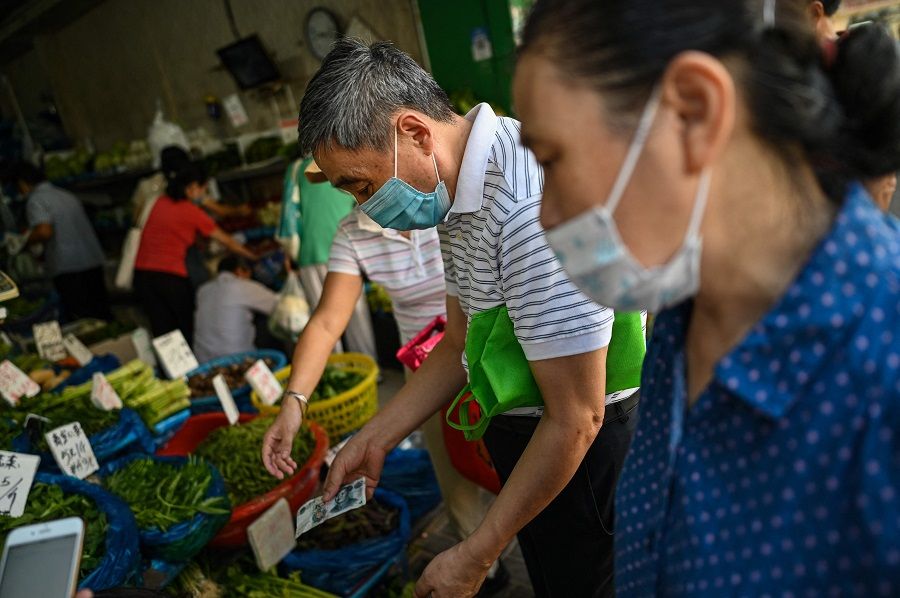People buy vegetables at a shop in Shanghai, China, on 28 September 2021. (Hector Retamal/AFP)
