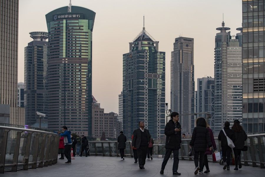 Pedestrians walk on an overpass in the Lujiazui financial district in Shanghai, China, 21 December 2020. (Qilai Shen/Bloomberg)