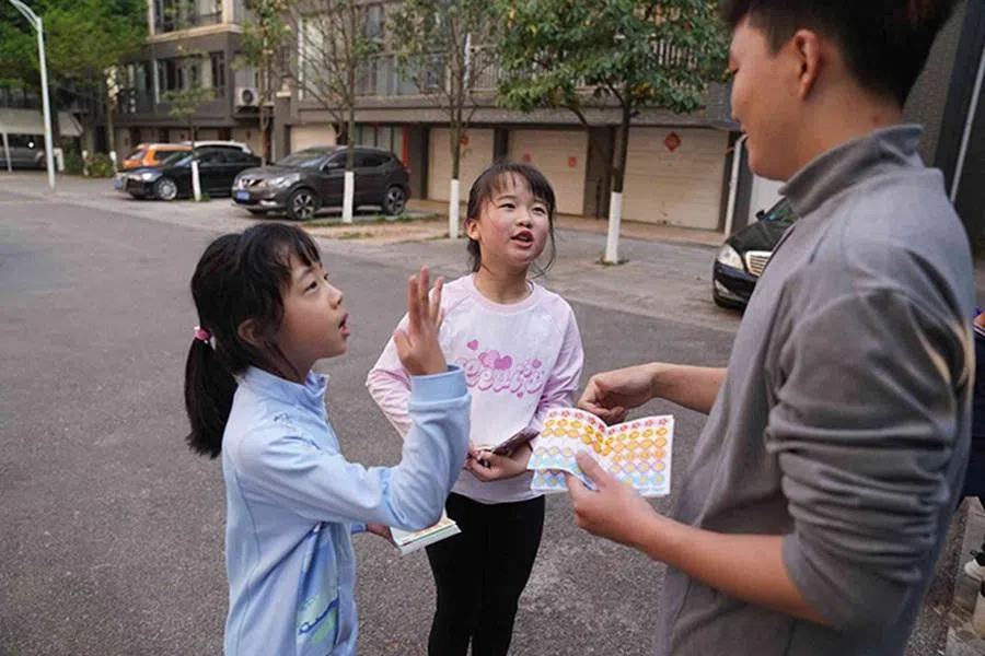 Hu Yutao hands out stickers as a reward at the end of a session to help keep his students motivated.