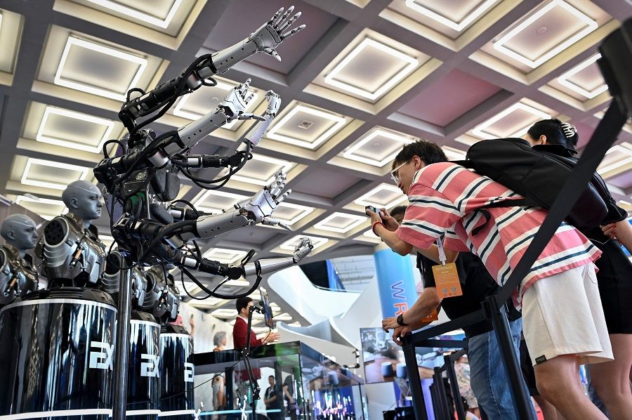 Visitors take pictures of robot arms at the 2023 World Robot Conference in Beijing on 16 August 2023. (Wang Zhao/AFP)