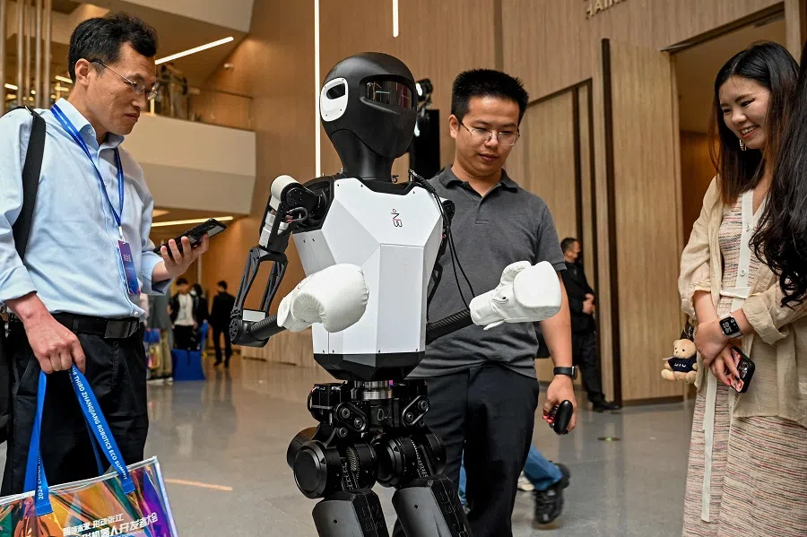 Visitors look at a humanoid robot at the 2024 China Humanoid Robot Developers Conference in Shanghai on 6 June 2024.  (AFP)