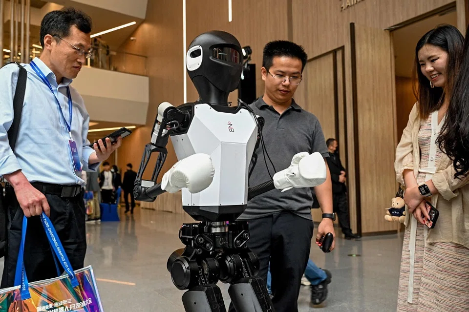 Visitors look at a humanoid robot at the 2024 China Humanoid Robot Developers Conference in Shanghai on 6 June 2024.  (AFP)