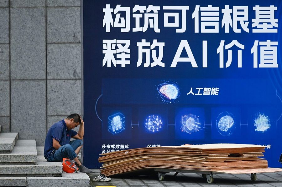 A worker rests outside the venue hosting the World Artificial Intelligence Conference (WAIC) in Shanghai, China, on 5 July 2023. (Wang Zhao/AFP)