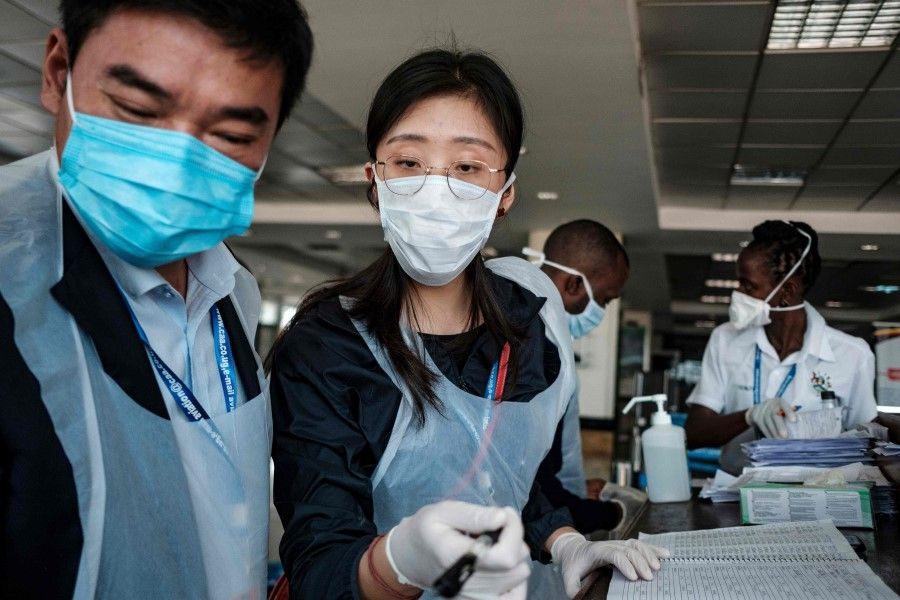 Chinese embassy officials alongside airport personnel prepare for passengers arriving on international flights at the port health desk where they are screened for signs of the novel coronavirus at Entebbe Airport on March 3, 2020. (Sumy Sadurni/AFP)