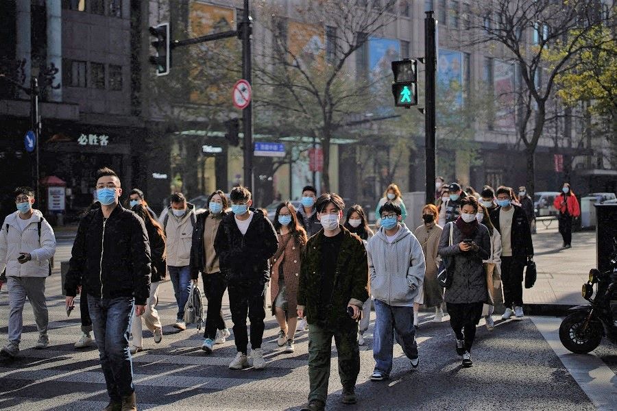 People wearing protective masks walk on a street in Shanghai, China, 20 December 2021. (Aly Song/File Photo/Reuters)