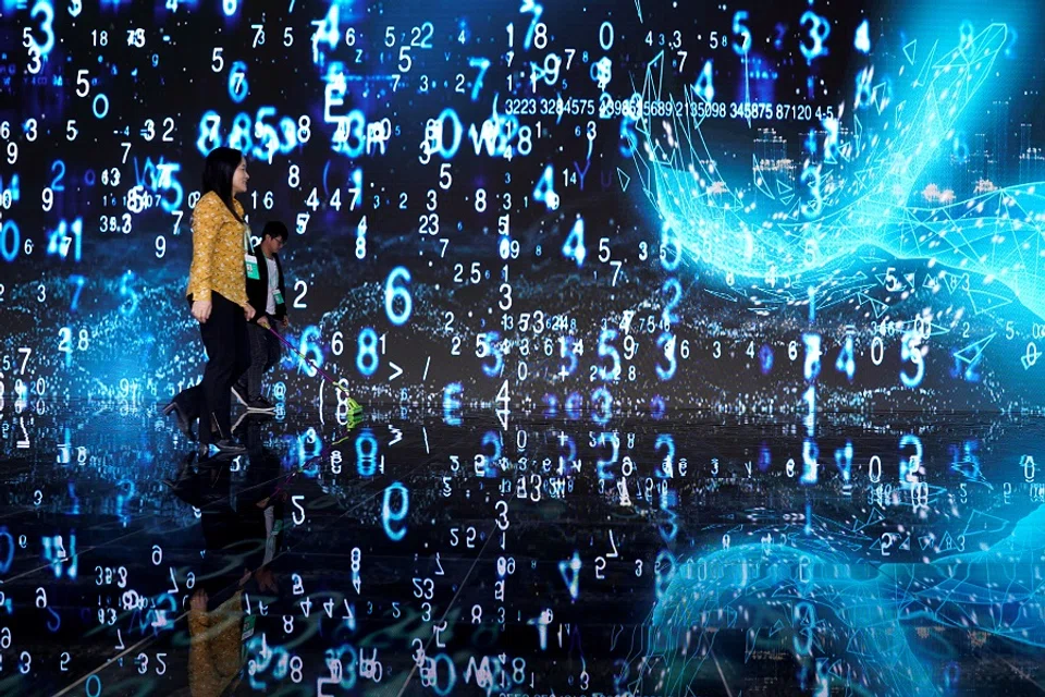 In this file photo taken on 20 October 2019, people walk in front of a screen at the World Internet Conference (WIC) in Wuzhen, Zhejiang province, China. (Aly Song/File Photo/Reuters)