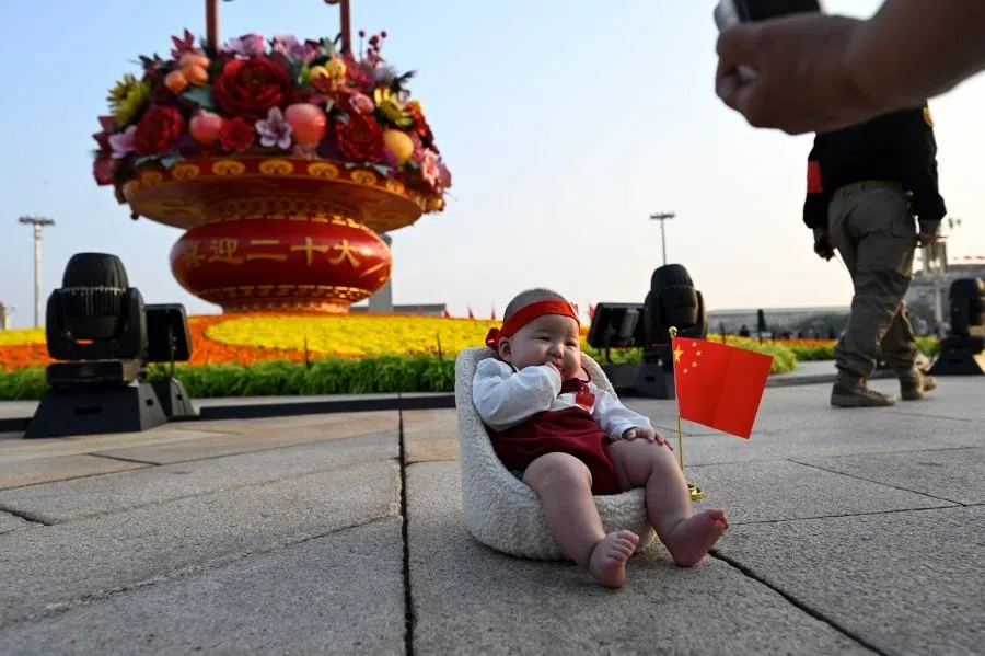 A woman takes a photo of a baby in front of an installation at Tiananmen Square in Beijing on 29 September 2022. (Jade Gao/AFP)