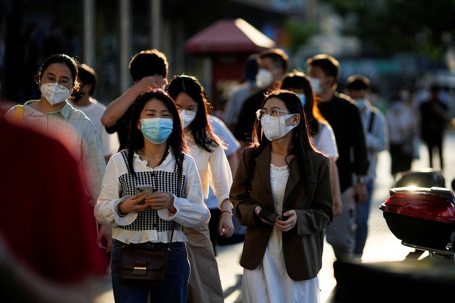 Office workers wearing protective face masks walk on a street in Shanghai, China, 7 June 2022. (Aly Song/File Photo/Reuters)
