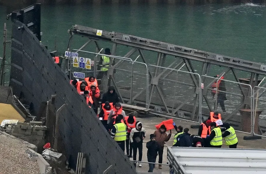 Migrants picked up at sea attempting to cross the English Channel from France, walk to a marquee for processing after disembarking from Border Force vessel 'Defender' at the Marina in Dover, southeast England, on 17 January 2024. (Ben Stansall/AFP)