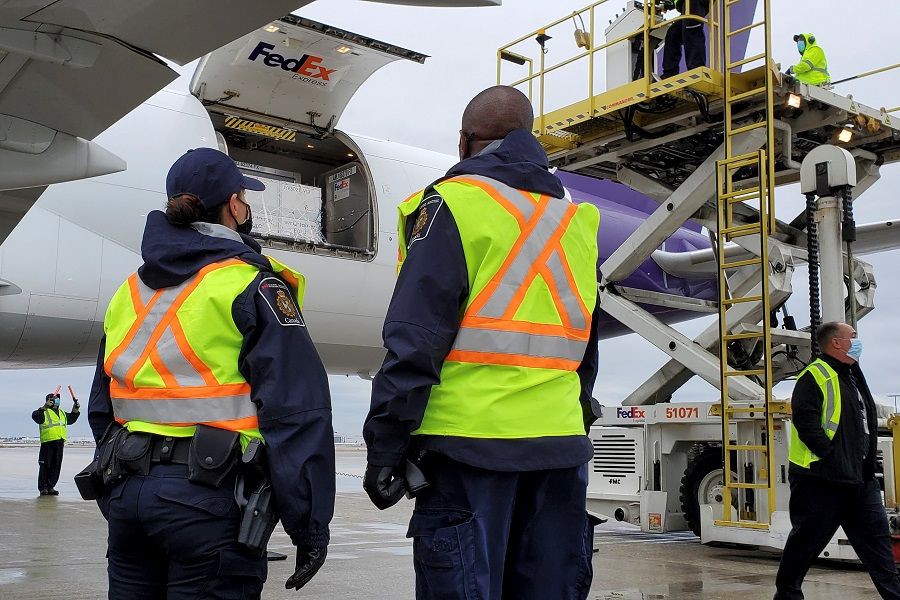 Canada Border Services Agency (CBSA) officers watch as the first shipment of newly authorised Moderna Covid-19 vaccine is unloaded from a Fedex cargo jet at a port of entry in Canada, 24 December 2020. (Canada Border Services Agency/Handout via Reuters)