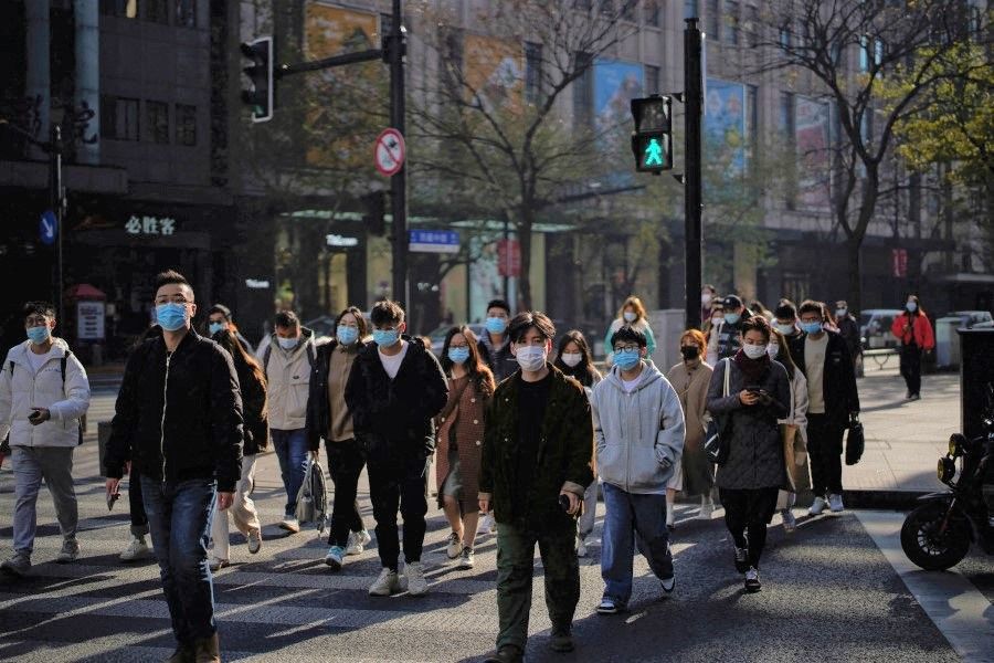 People wearing protective masks walk on a street, following new cases of the coronavirus disease (COVID-19), in Shanghai, China, 20 December 2021. (Aly Song/Reuters)
