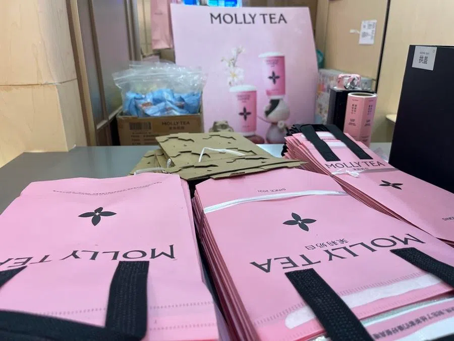 Packaging bags featuring Molly Tea’s logo, and a display board showing Molly Tea drinks, Kaide Mall (Sun Palace Shop) in Beijing, taken on 8 July 2026.