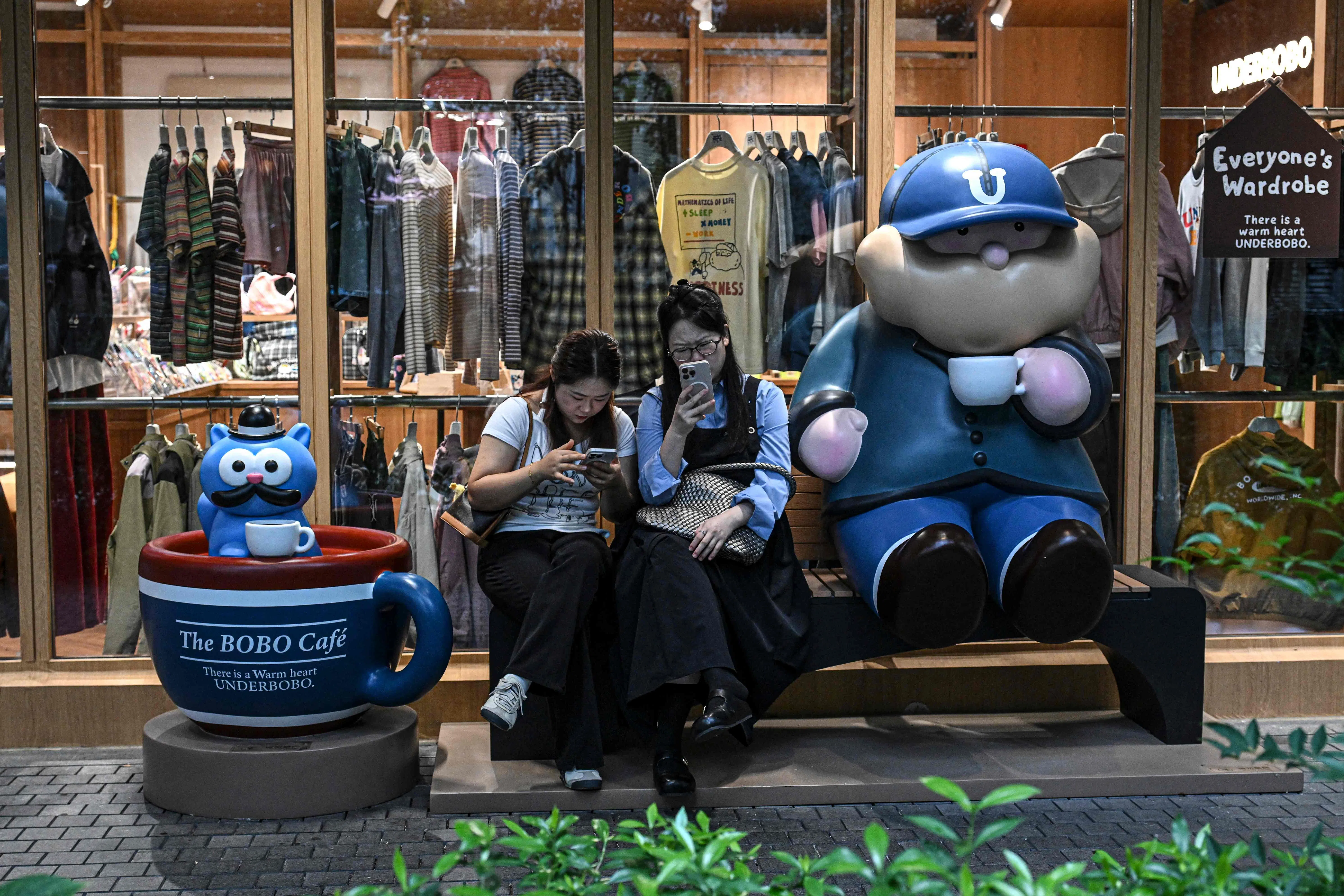 People check on their phones outside a clothing shop in Shanghai on 11 September 2026.