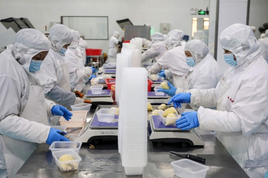 Workers package frozen durian at a food factory in Hangzhou, in China's eastern Zhejiang province on 3 February 2023. (AFP)