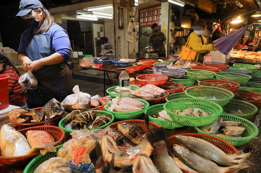A woman wearing a face mask works at a fish stall in a market in Taipei, Taiwan, 26 November 2021. (Annabelle Chih/Reuters)